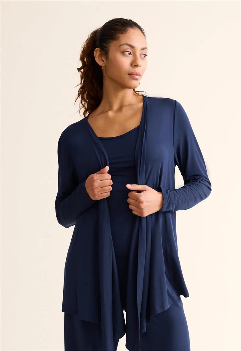 Woman wearing a navy blue cardigan over a matching outfit on a beige background