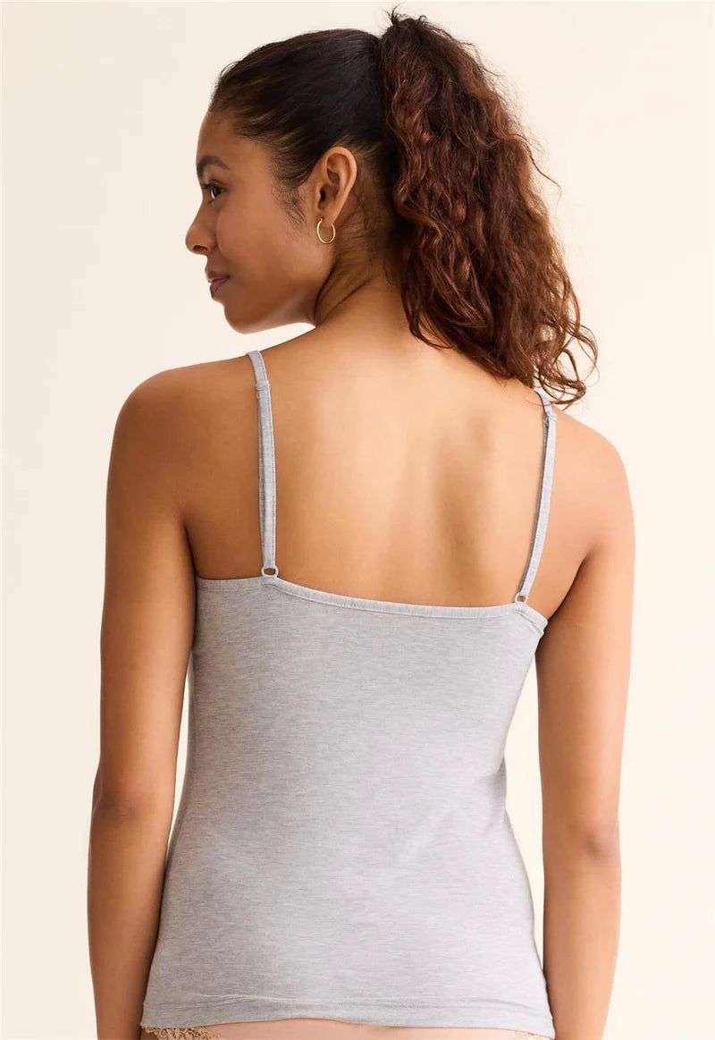 Woman wearing a gray tank top with thin straps on a beige background