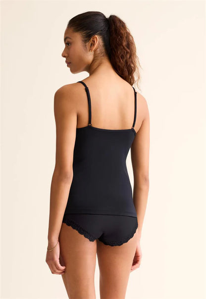 Woman wearing a black tank top and shorts on a beige background