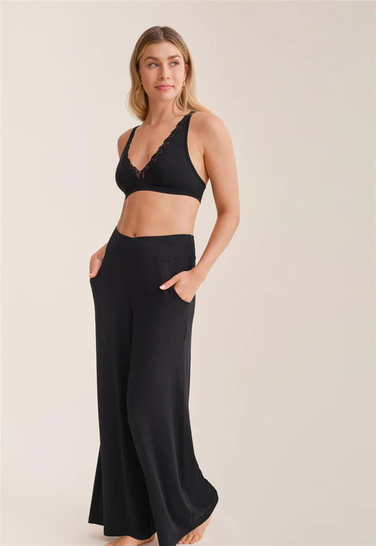 Woman wearing a black sports bra and wide-leg pants on a beige background