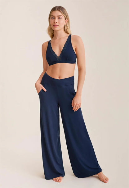 Woman wearing a navy blue bralette and wide-leg pants on a beige background
