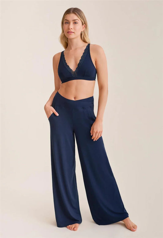 Woman wearing a navy blue bralette and wide-leg pants on a beige background