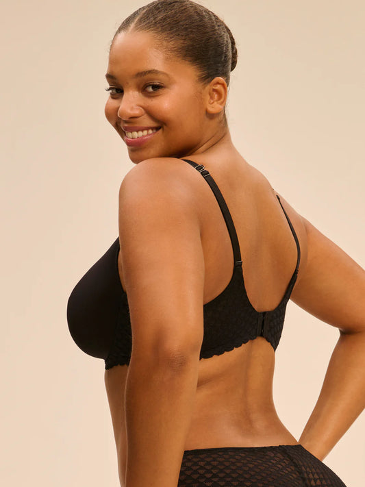 Woman wearing a black bra against a beige background