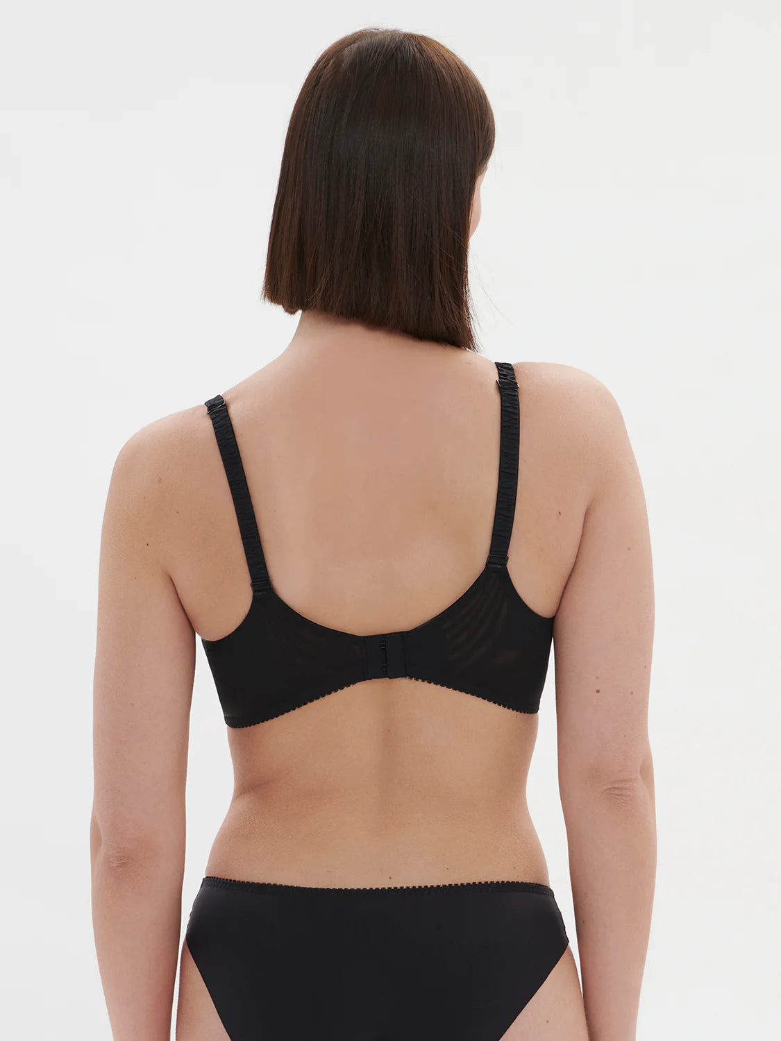 Person wearing a black bra and underwear set on a white background
