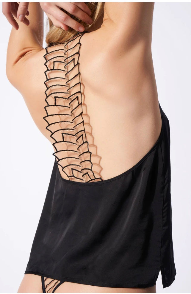 Person wearing a black garment with a detailed illustration of a spine on the back against a white background