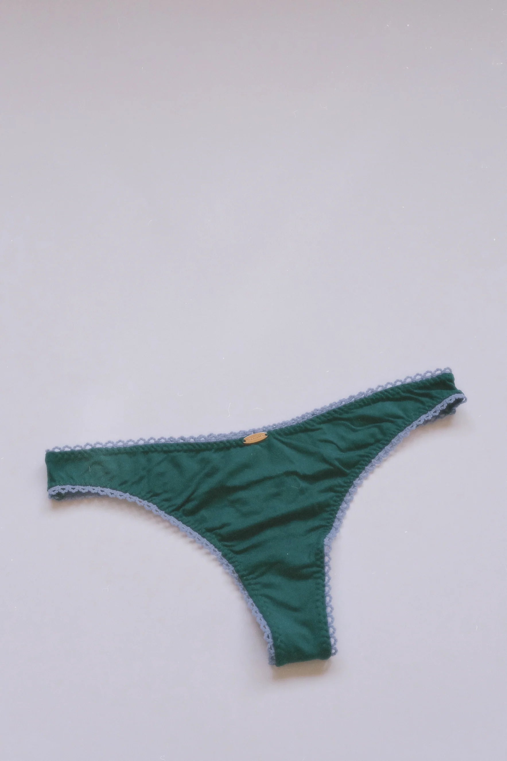 Green bikini bottom with white trim on a light gray background