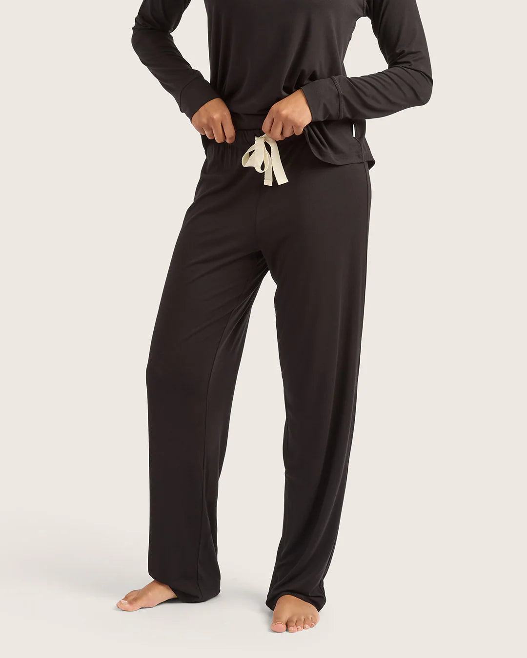 Person wearing black pajama set with white drawstring on a white background