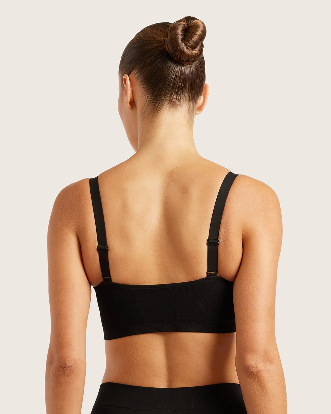 Woman wearing a black bra against a plain background