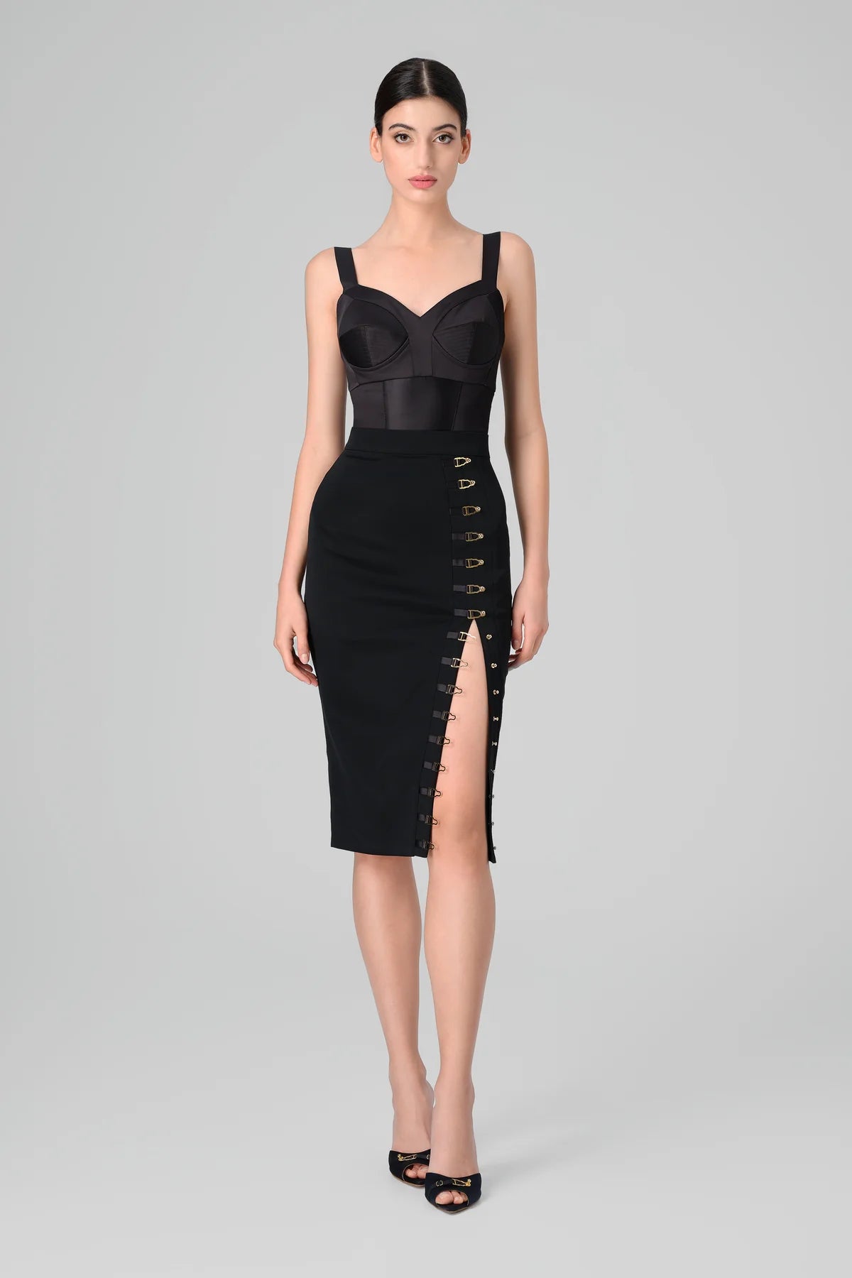 Black skirt with a front slit worn by a model on a gray background