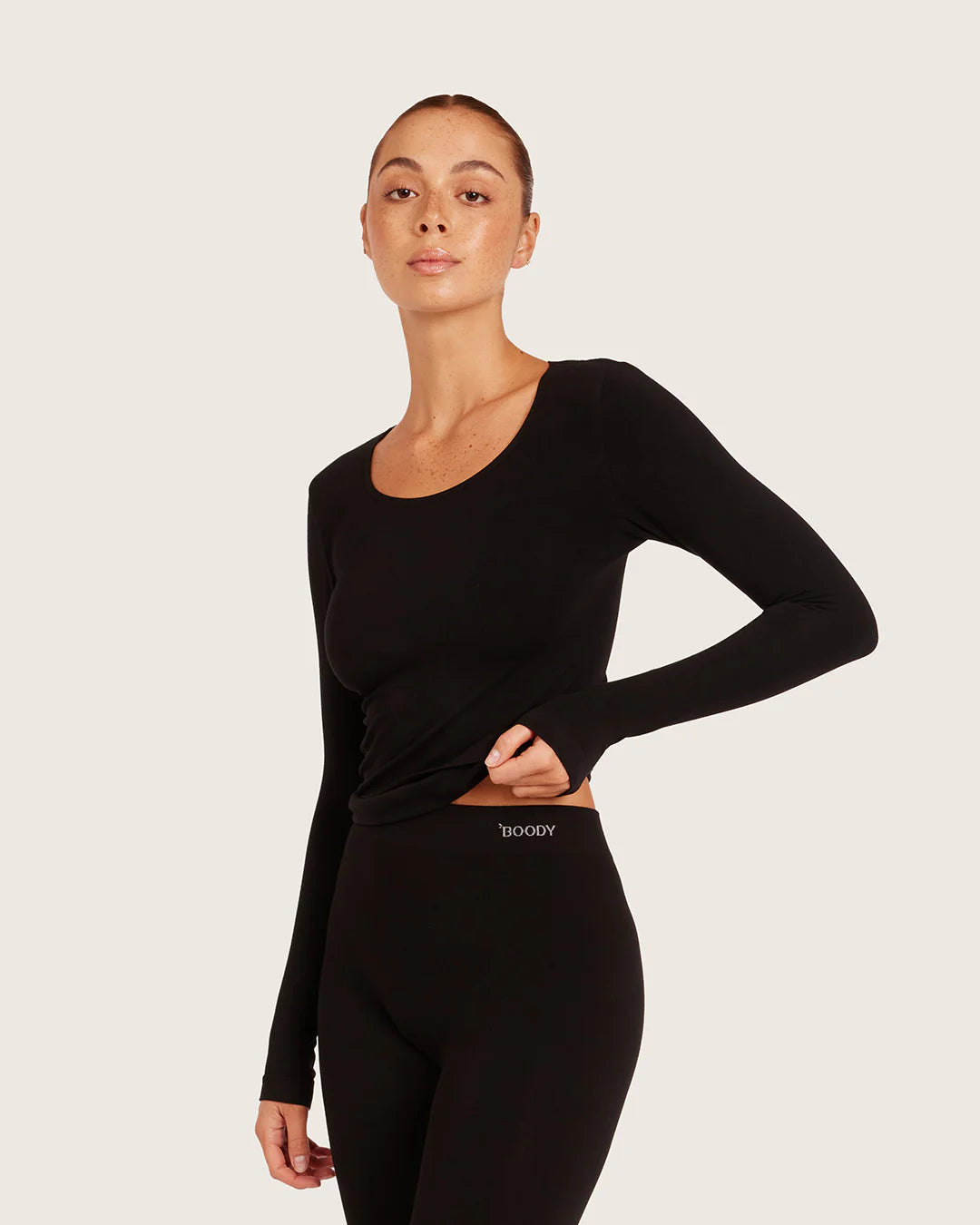 Person wearing a black long-sleeve top and leggings on a light gray background