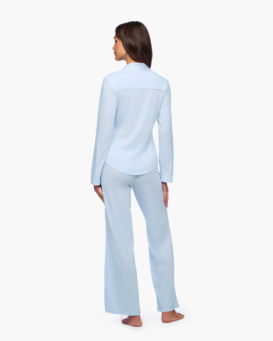 Woman wearing light blue pajama set on a white background