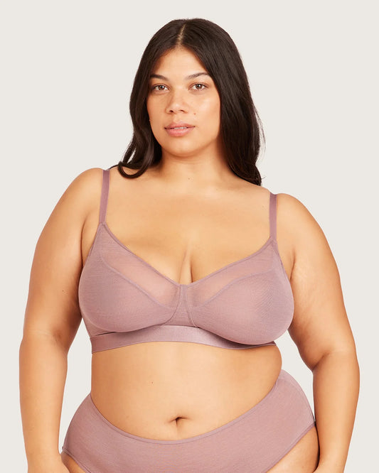 A plus-size model wearing a dusty mauve mesh and solid bralette with matching high-waisted briefs, photographed against a solid light gray background.