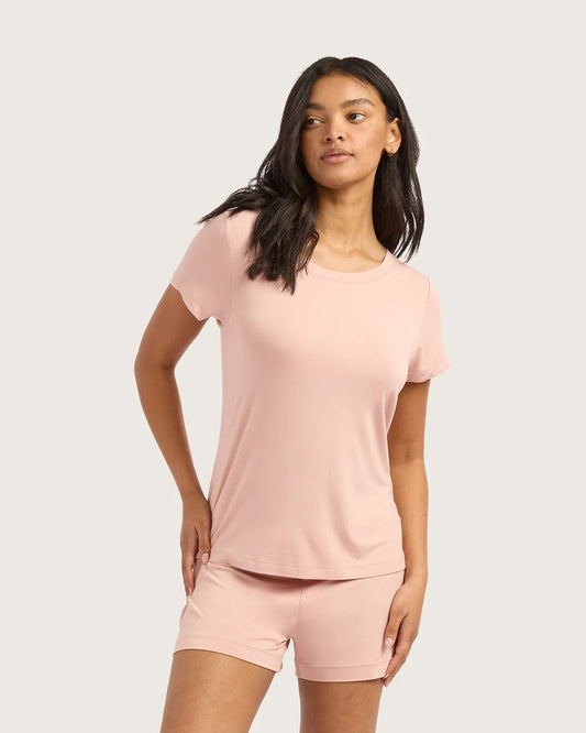 Woman wearing a pink t-shirt and shorts set on a plain background