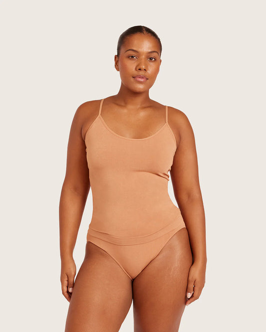 Woman wearing a beige swimsuit against a plain background