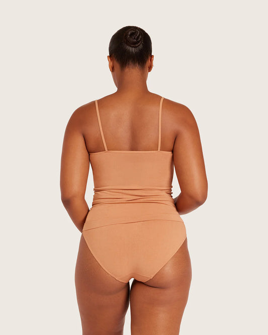 Person wearing a tan swimsuit on a plain background