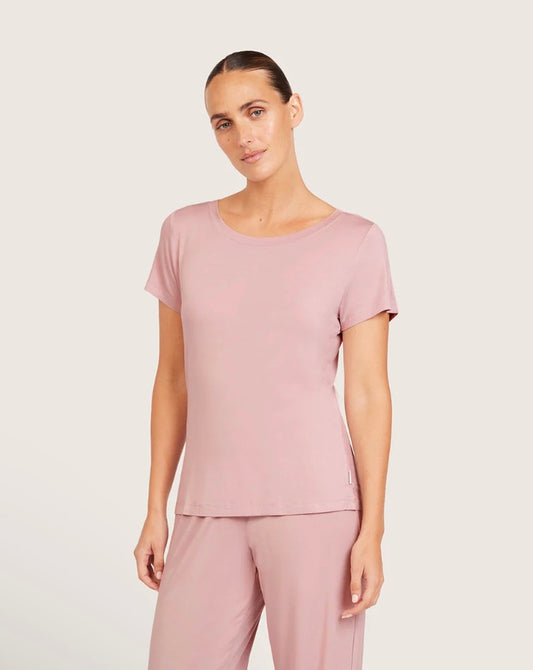 Woman wearing a pink top and pants on a light gray background
