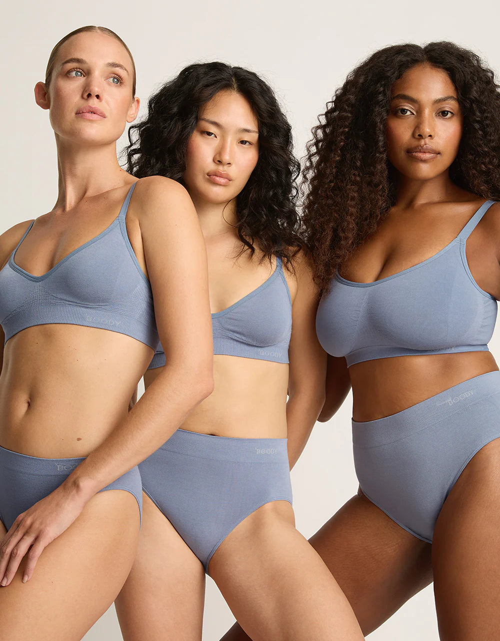 Three women wearing matching blue lingerie sets against a neutral background