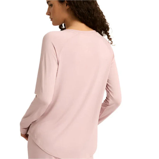 Pink long-sleeve top worn by a person on a white background