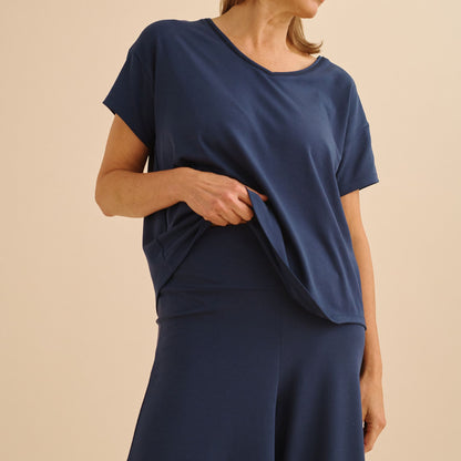 Person wearing a navy blue top and pants on a beige background