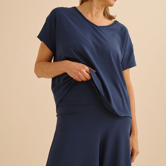 Person wearing a navy blue top and pants on a beige background