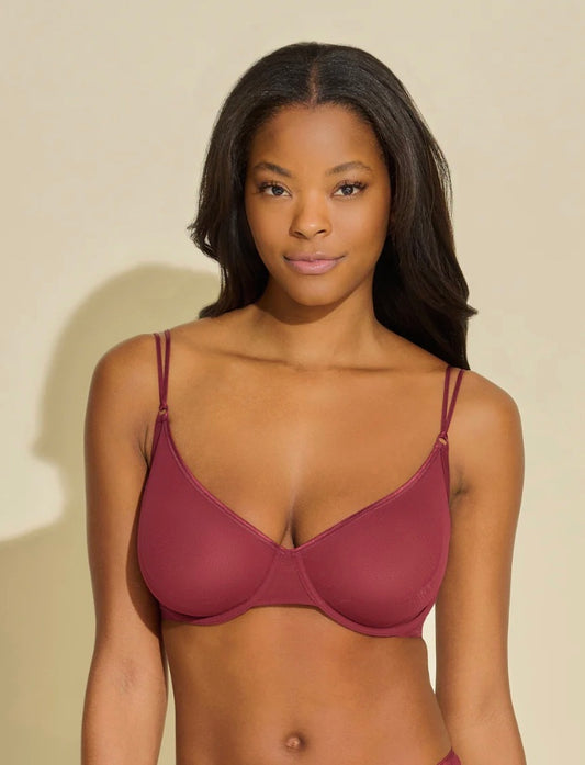 Woman wearing a maroon bra against a beige background