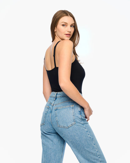 Woman wearing a black tank top and blue jeans on a white background