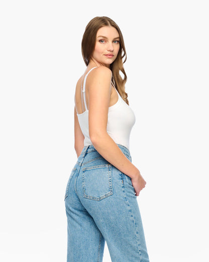 Woman wearing a white tank top and blue jeans on a white background
