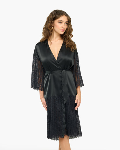 Woman wearing a black satin robe with lace sleeves and hem on a white background