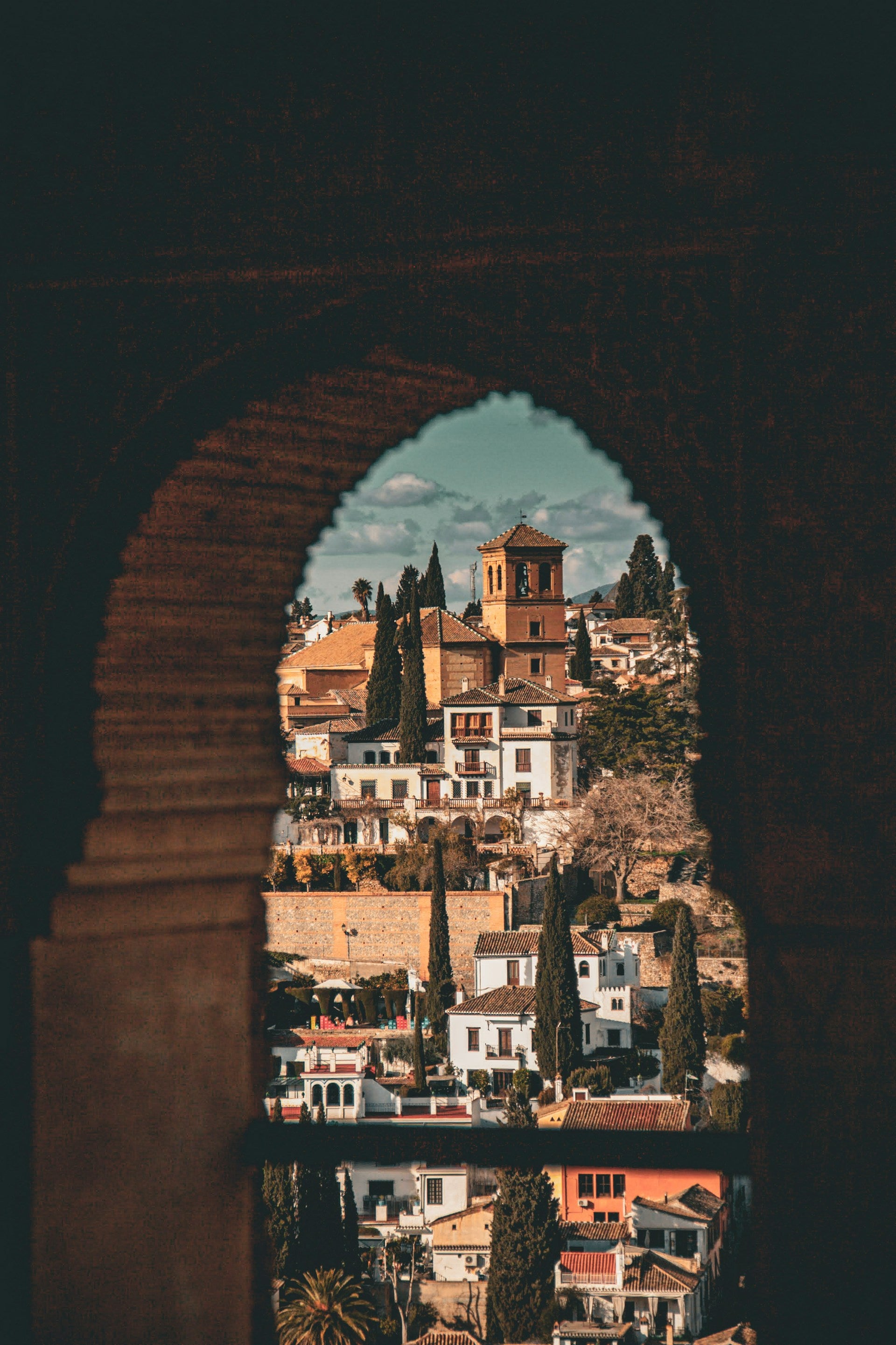 View of a town from behind an archway with a castle-like building.