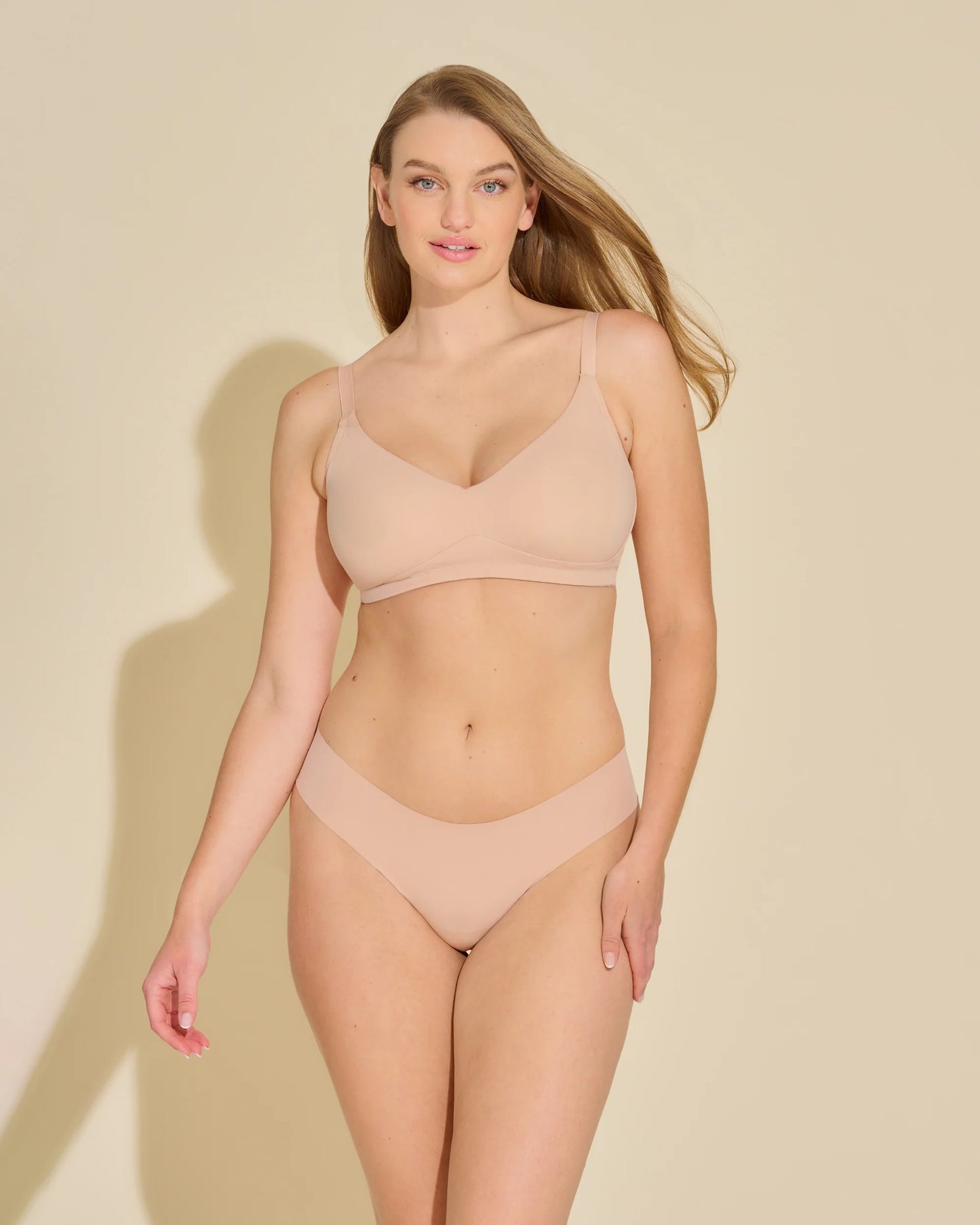 Woman wearing a beige bikini set against a beige background
