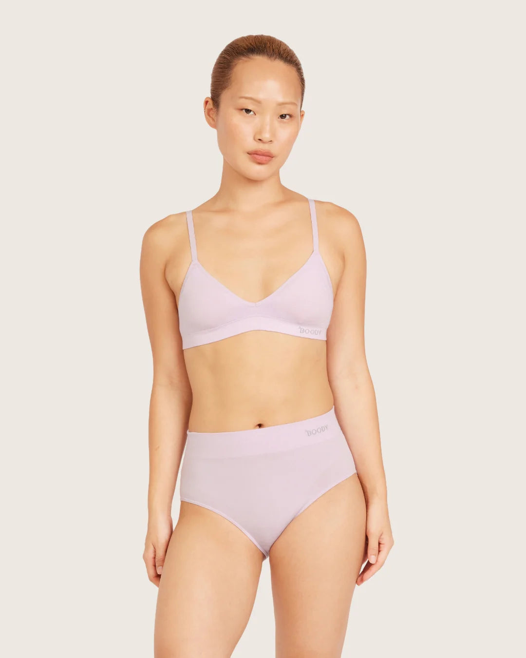 Woman wearing a light purple bikini set on a plain background