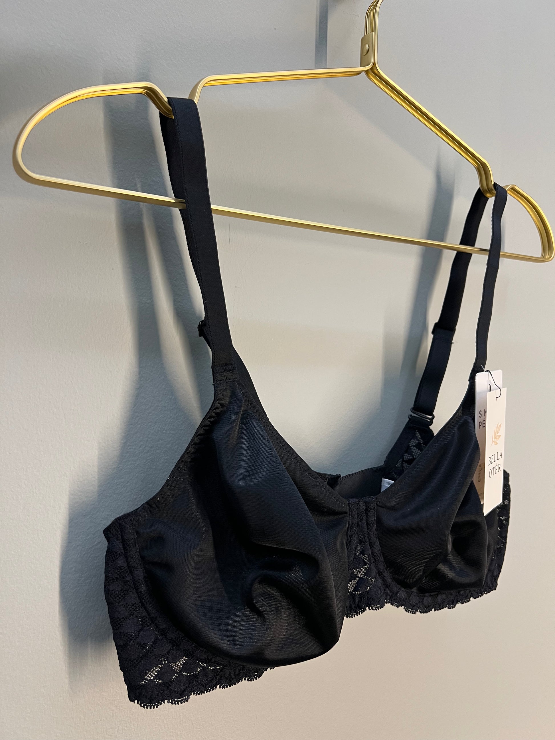 Black lace bra and panties set on a gold hanger against a gray background
