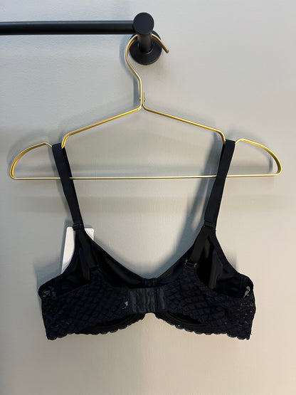 Black bra on a gold hanger against a light background