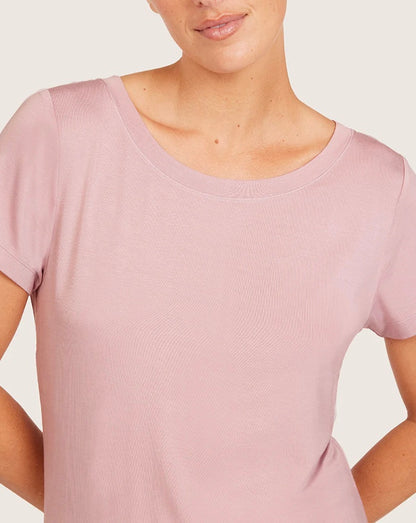 Person wearing a light pink short-sleeve top against a plain background
