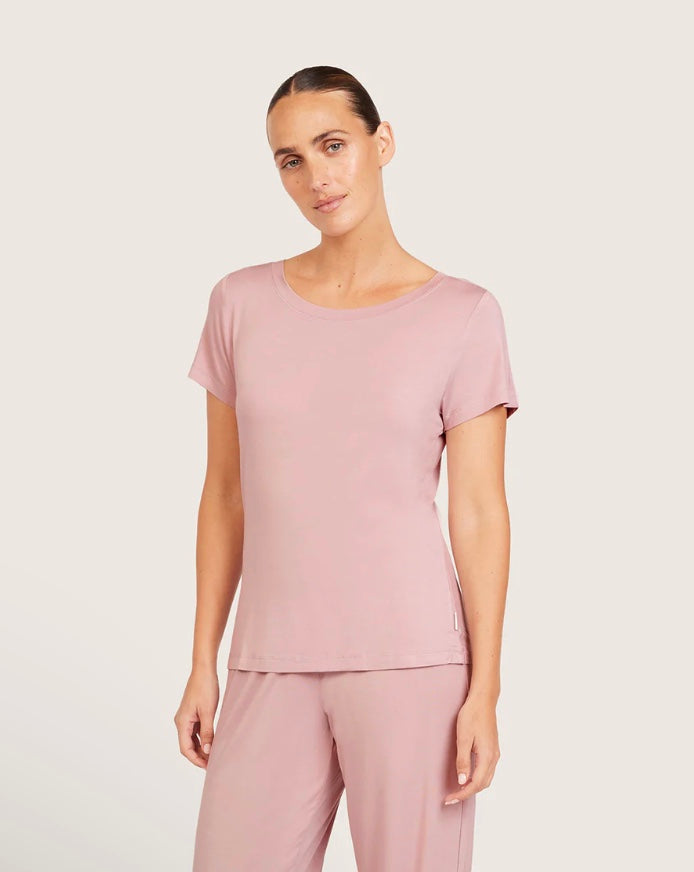 Woman wearing a pink top and pants on a light gray background