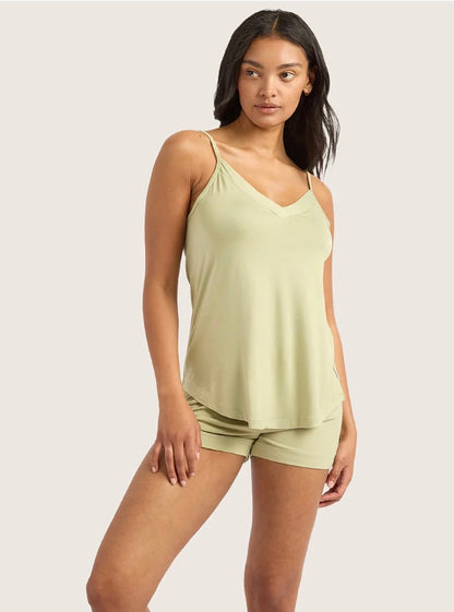 Woman wearing a light green tank top and shorts set on a plain background
