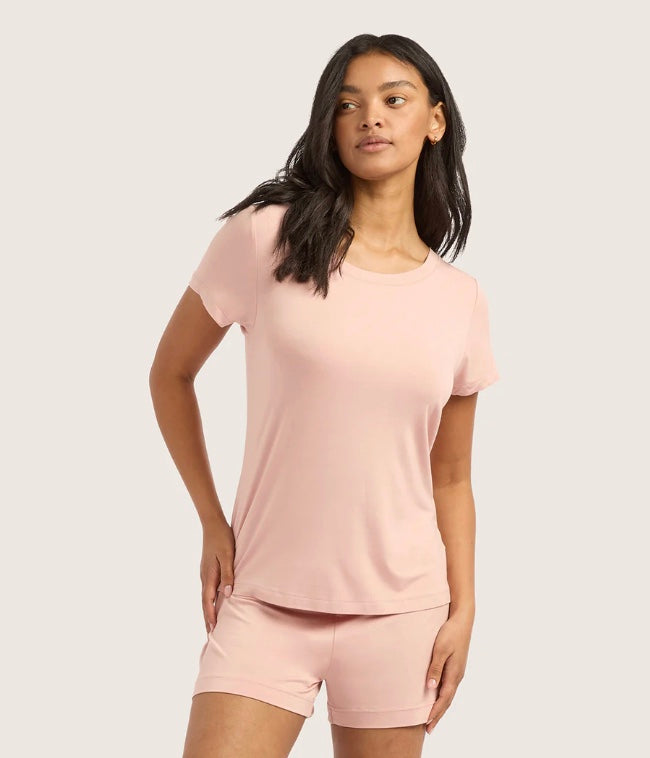 Woman wearing a pink t-shirt and shorts set on a light gray background