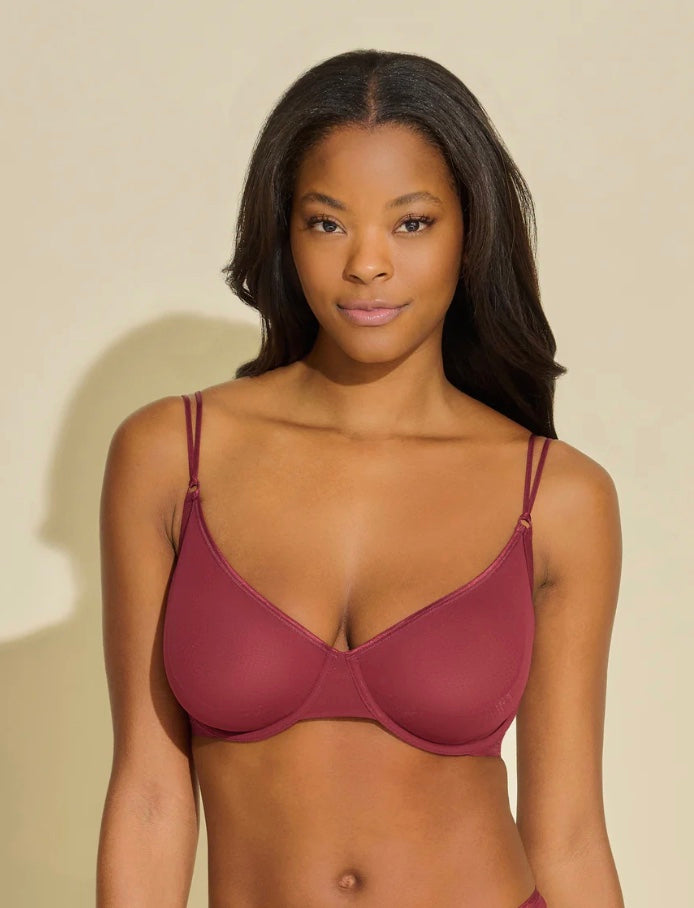 Woman wearing a maroon bra against a beige background