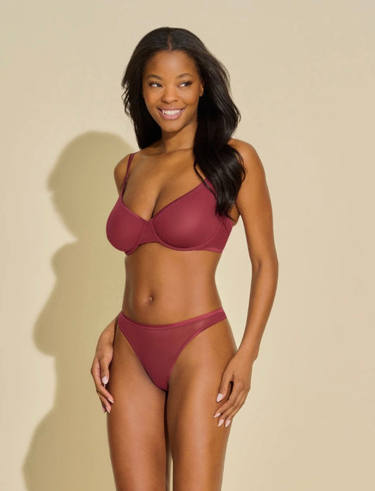 Woman wearing a maroon bikini against a beige background