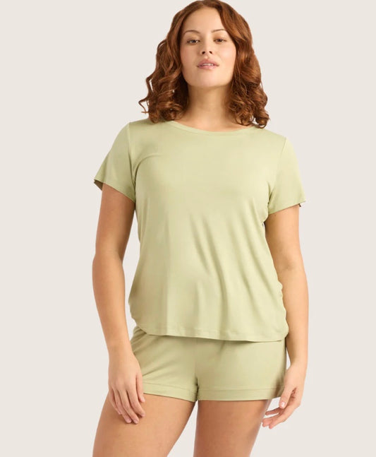 Woman wearing a light green t-shirt and shorts set on a plain background