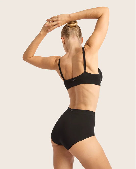 Person wearing a black sports bra and high-waisted underwear on a plain background