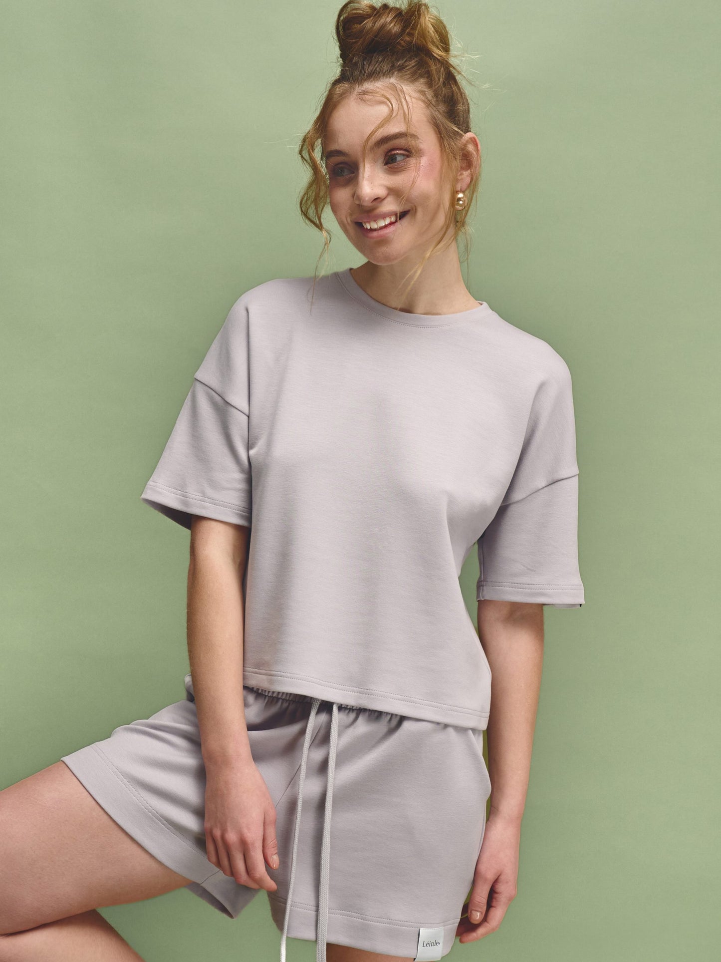 Woman wearing a gray outfit against a green background