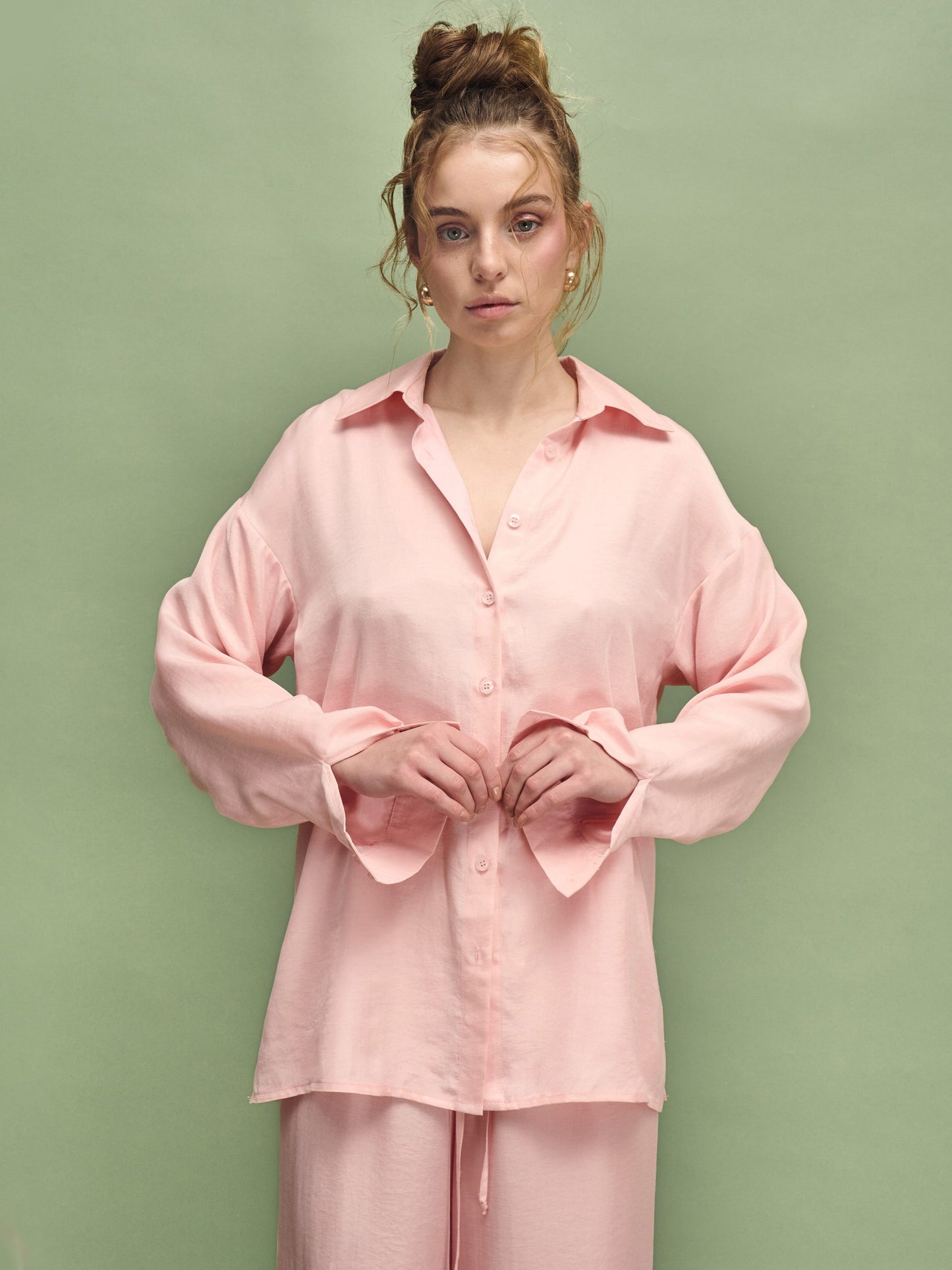 Woman wearing a pink pajama set against a green background