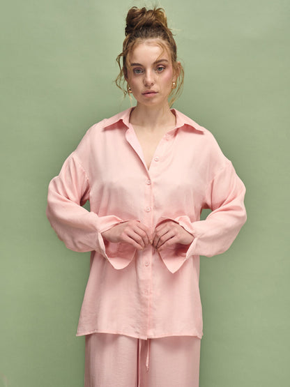 Woman wearing a pink pajama set against a green background