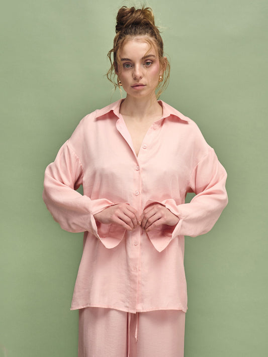 Woman wearing a pink pajama set against a green background