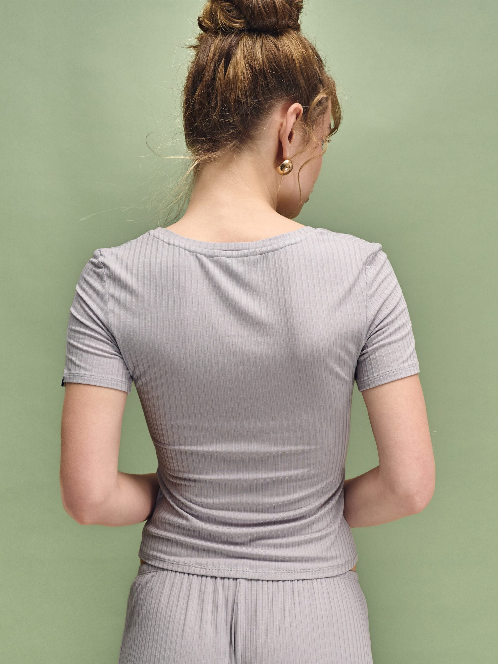 Woman wearing a light gray dress against a green background