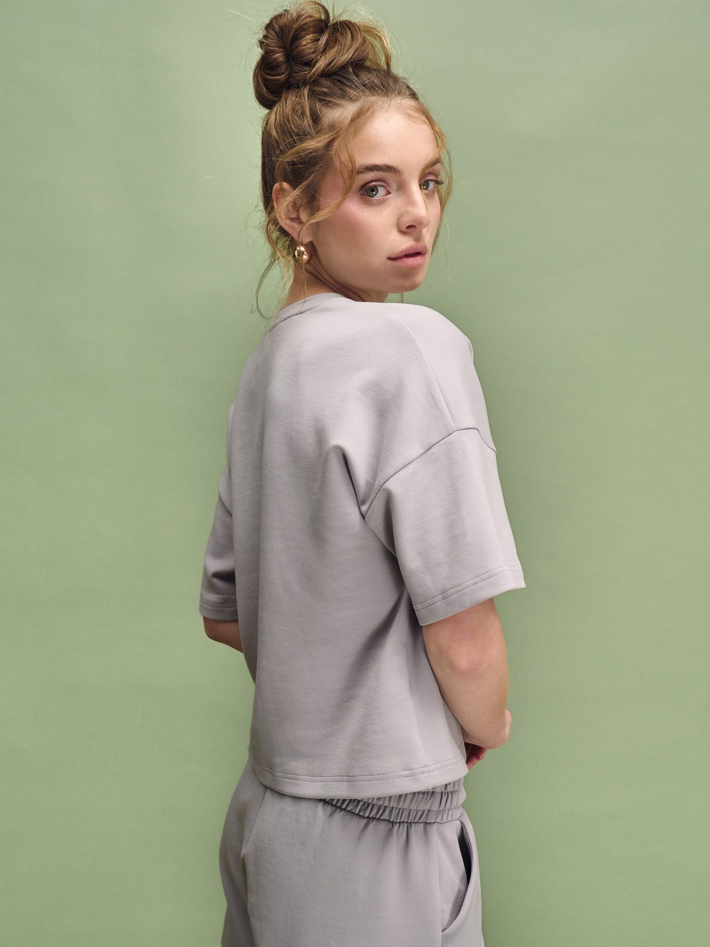 Woman wearing a gray outfit against a green background