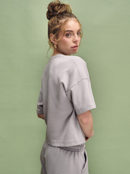 Woman wearing a gray outfit against a green background