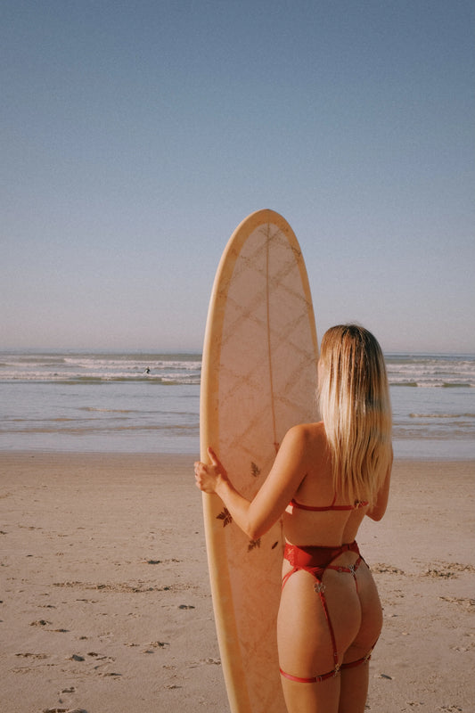 Woman holding a surfboard on a beach with a clear sky