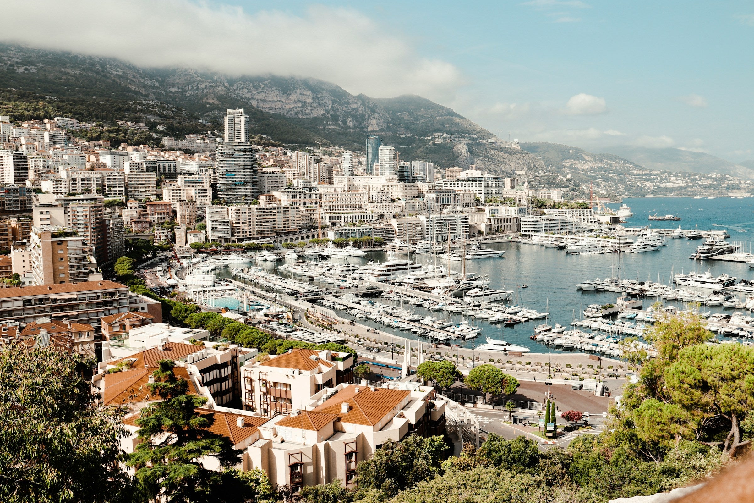 Cityscape with buildings, marina, and mountains in the background